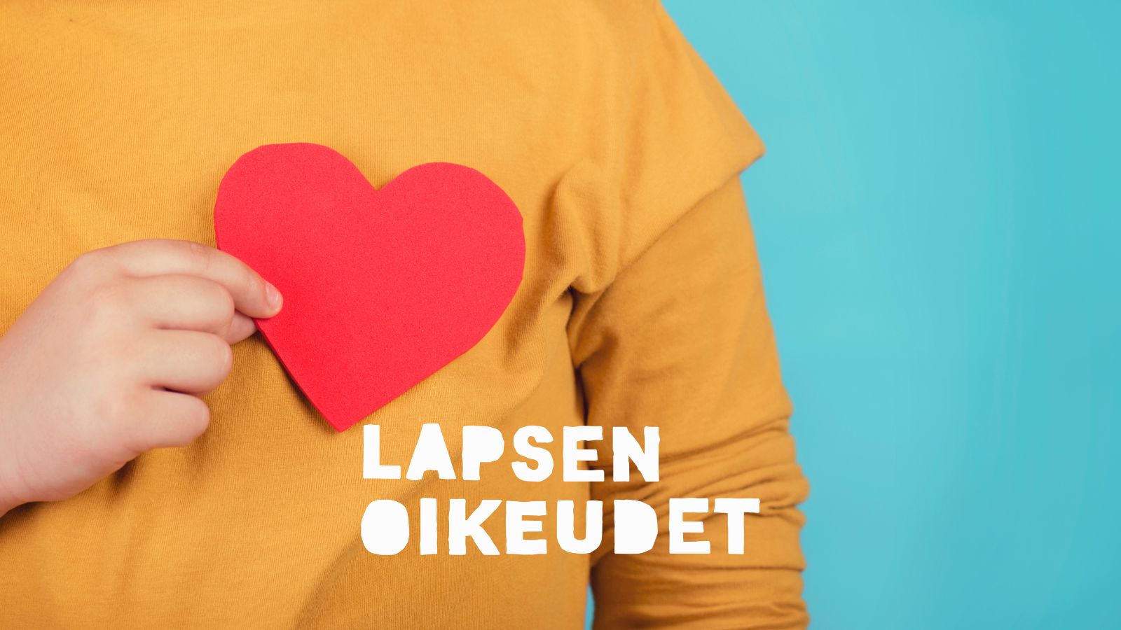 Lapsen käsi pitää paperisydäntä sydämen kohdalla.