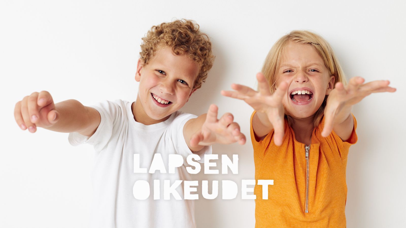 Kaksi lasta hymyilevät ja kurottavat kohti kameraa.